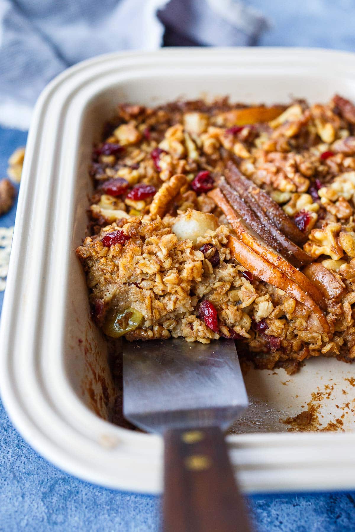 baked oatmeal in baking dish with spatula scooping out a piece