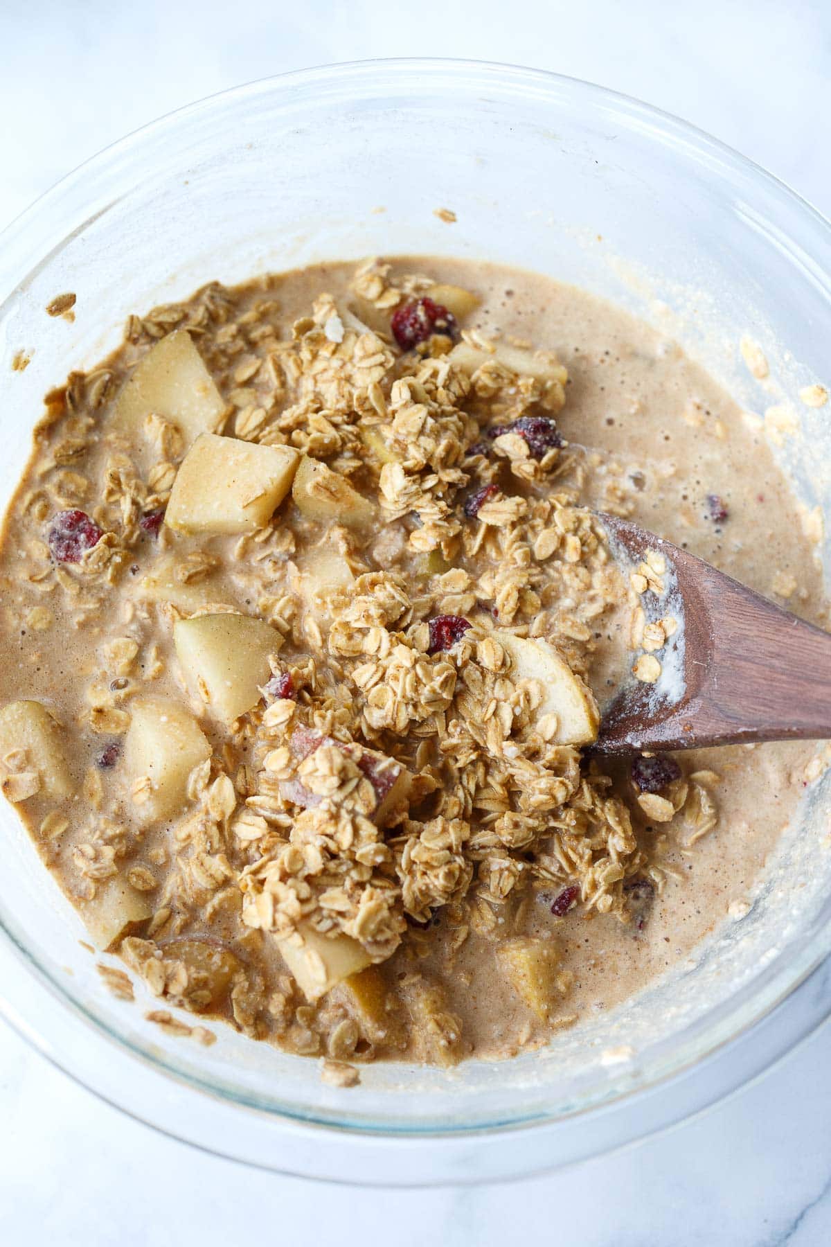 all ingredients for baked oatmeal in glass mixing bowl - milk, oats, pears, cranberries