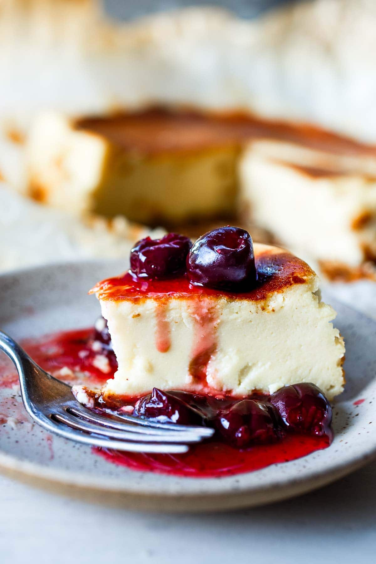 basque cheesecake on plate with fork and topped with berry compote