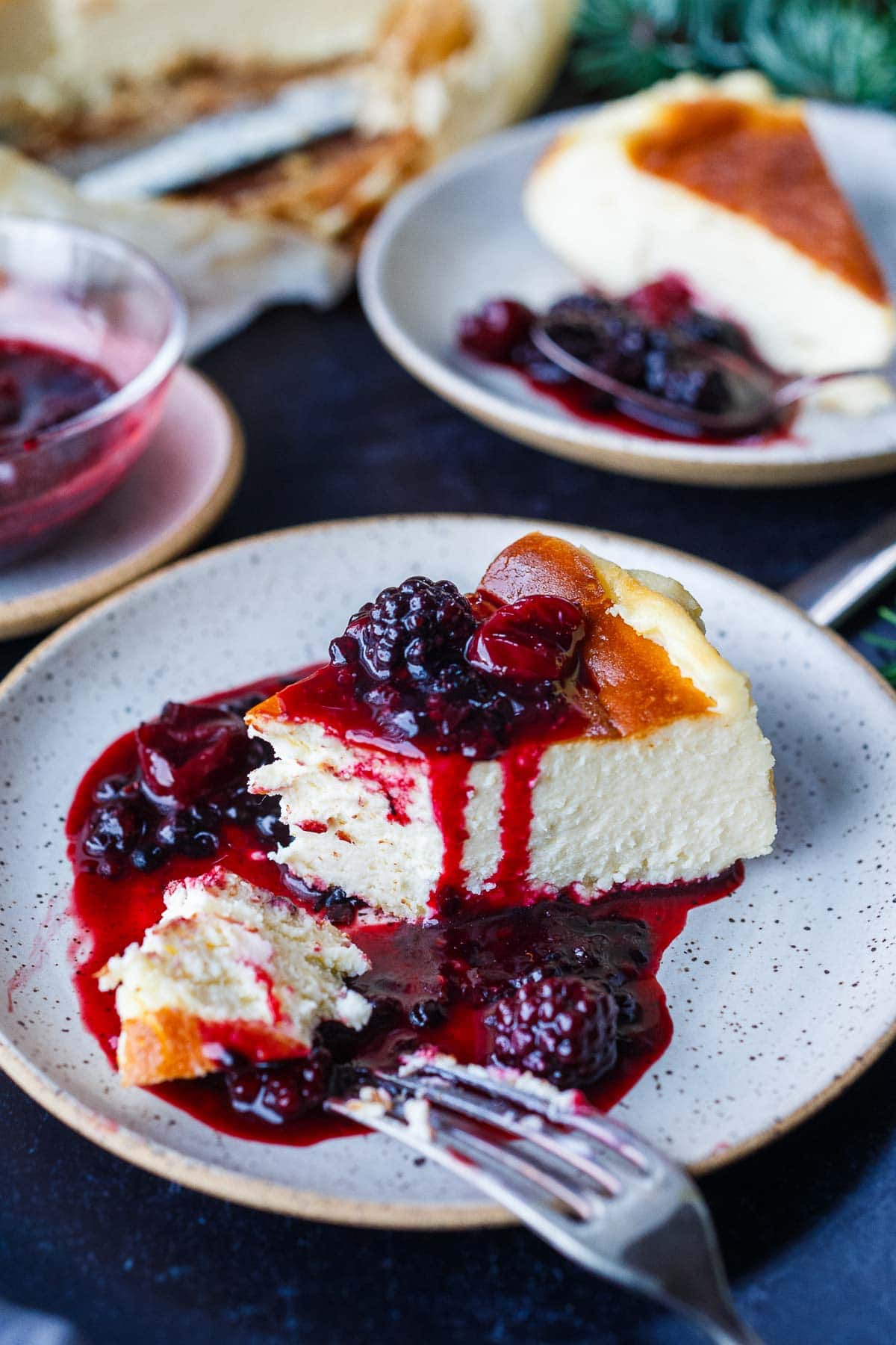 basque cheesecake slice on plate with berry compote over top