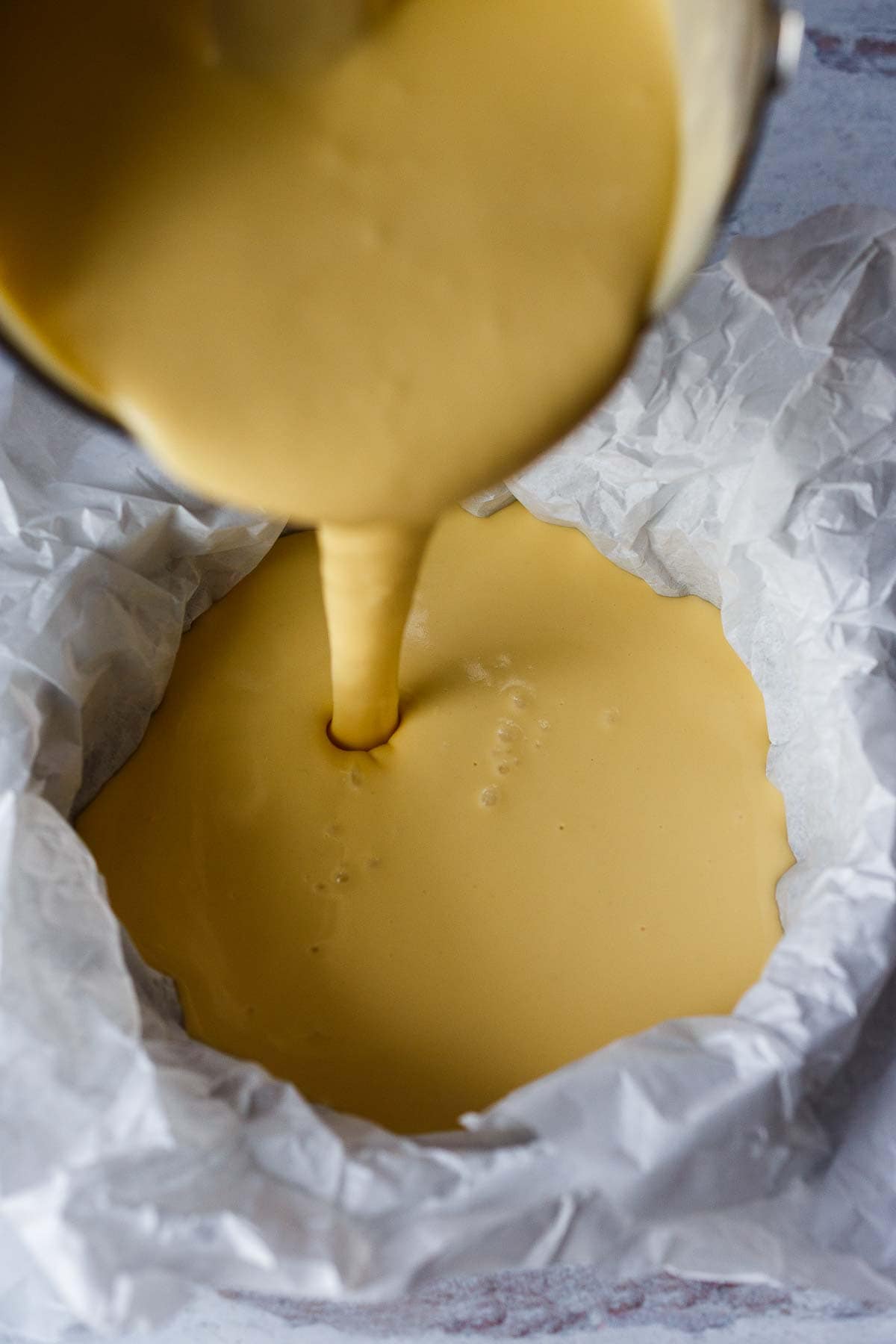 pouring basque cheesecake batter into parchment lined springform pan