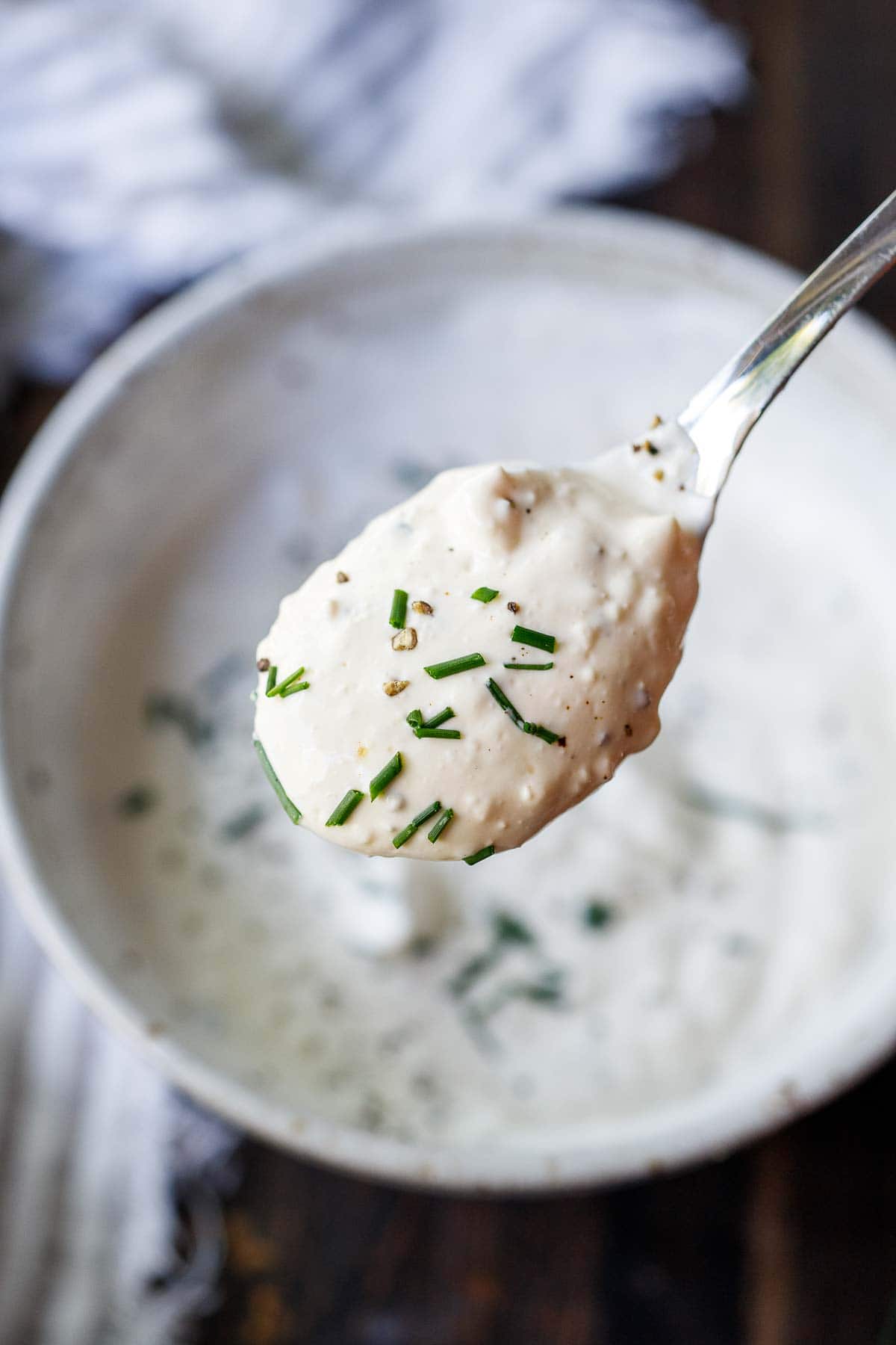 spoon holding up blue cheese dressing with fresh chives