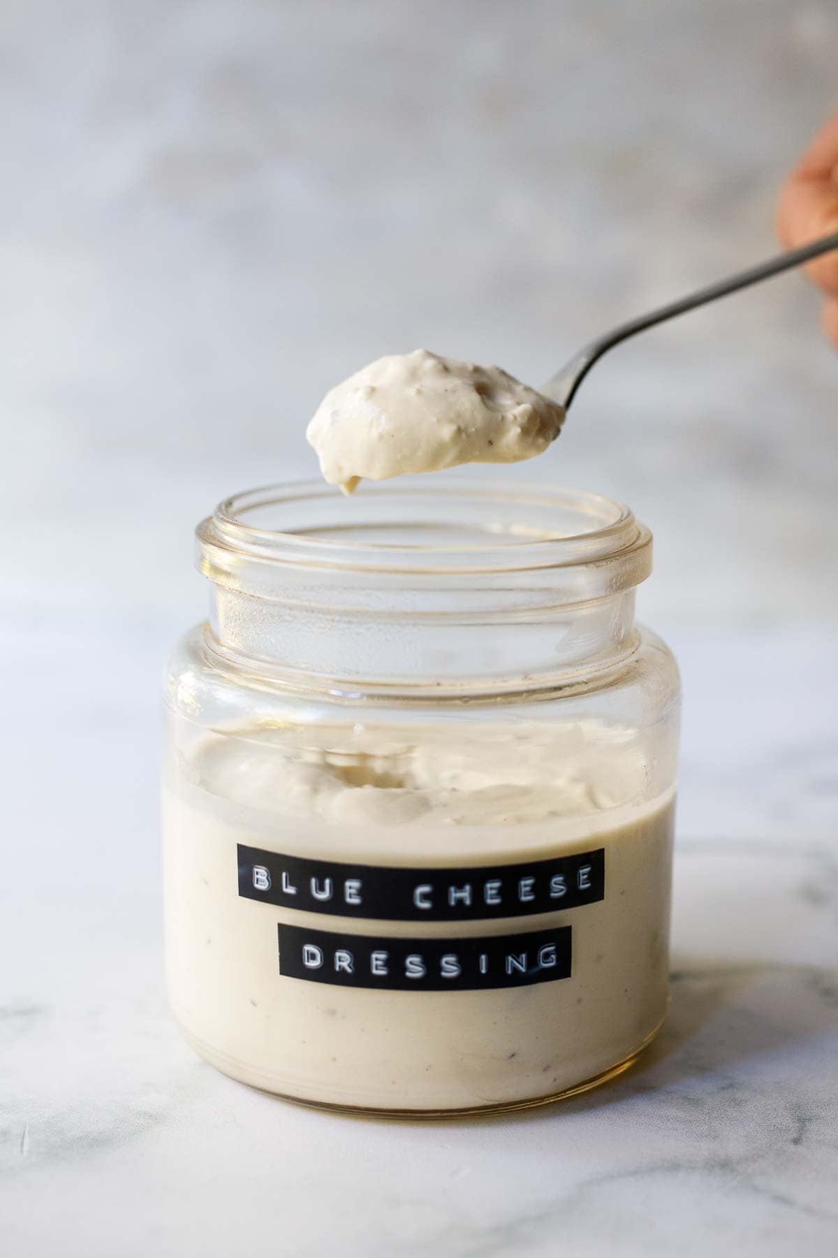 blue cheese dressing in glass jar with spoonful held over top