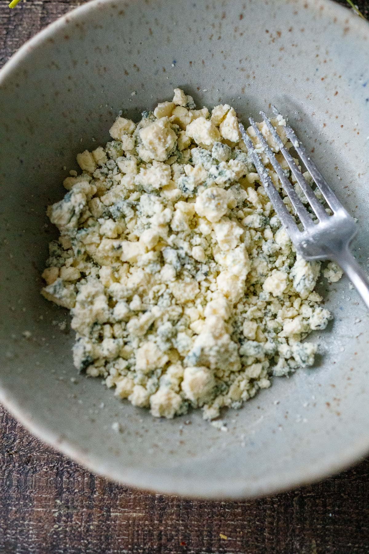 crumbled blue cheese in bowl, mashed with fork