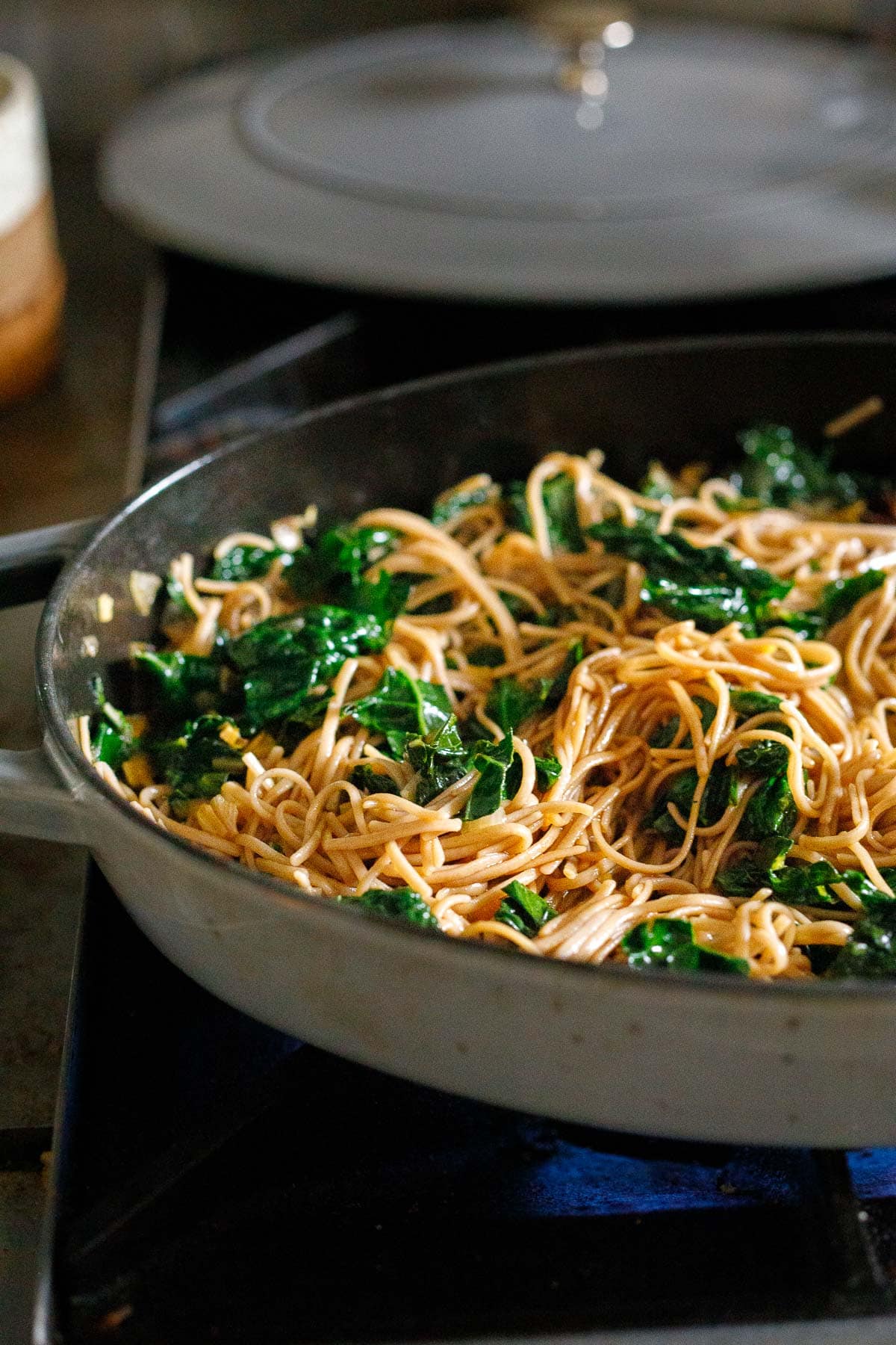 soba noodle stir fry in large skillet with wilted kale