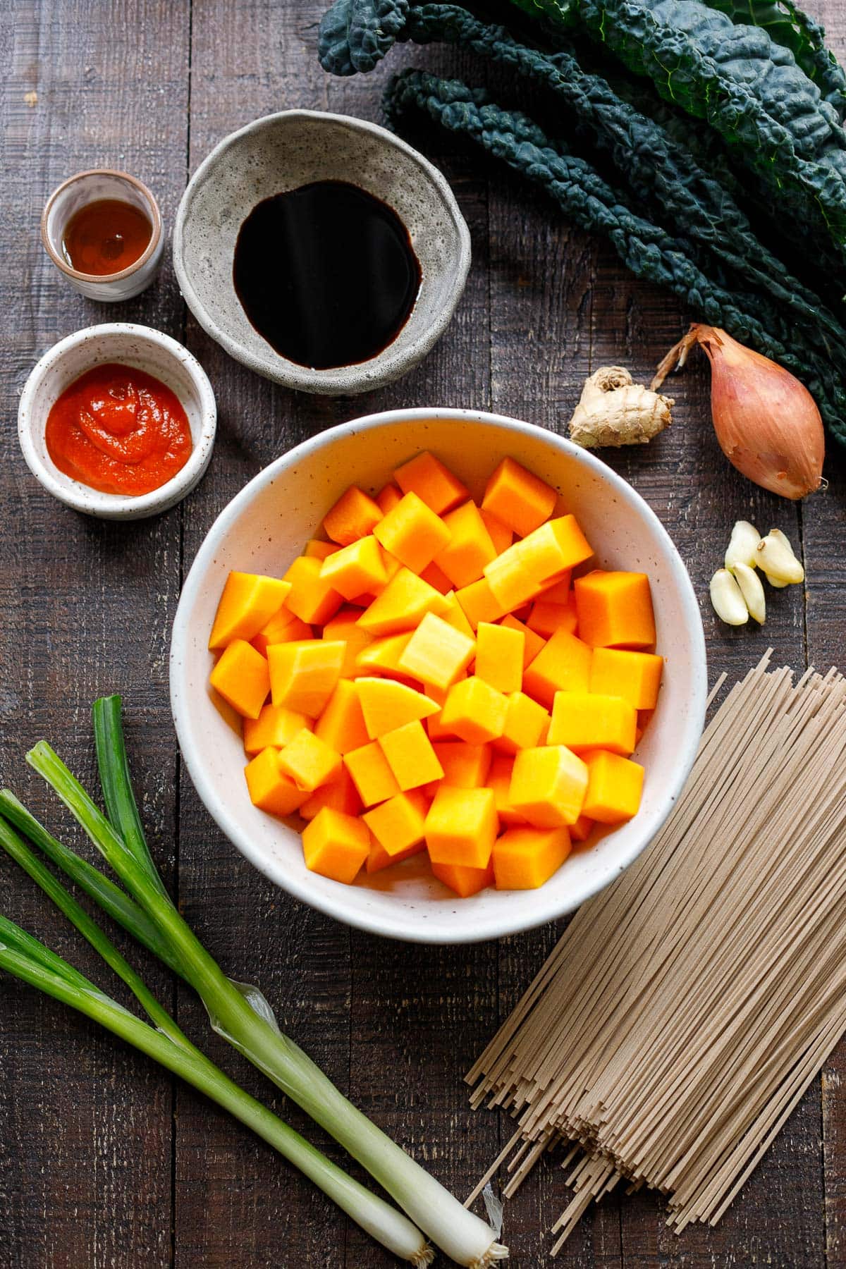 ingredients for butternut squash soba noodles - kale, shallot, ginger, garlic, cubed butternut squash, soba noodles, scallions, sauces.