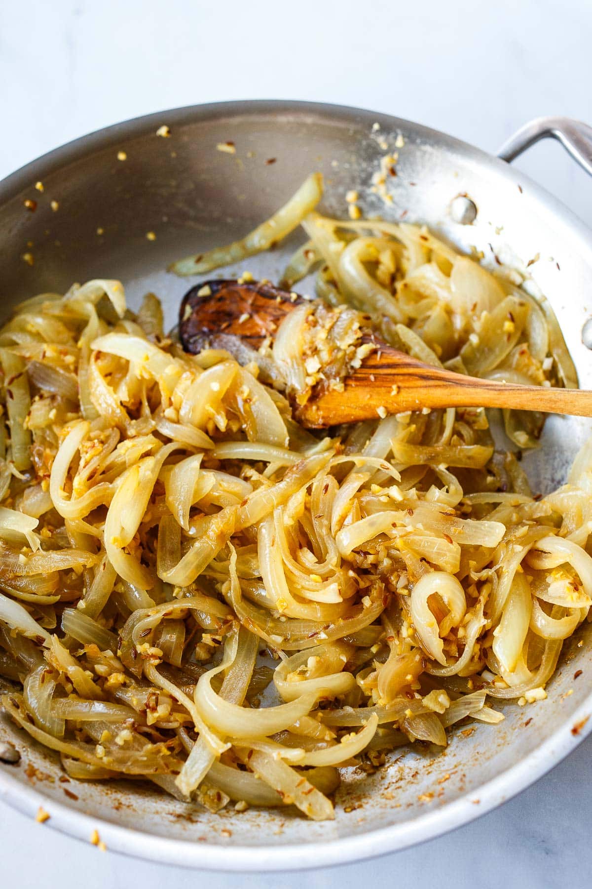 sliced caramelized onions in skillet mixed with garlic and ginger
