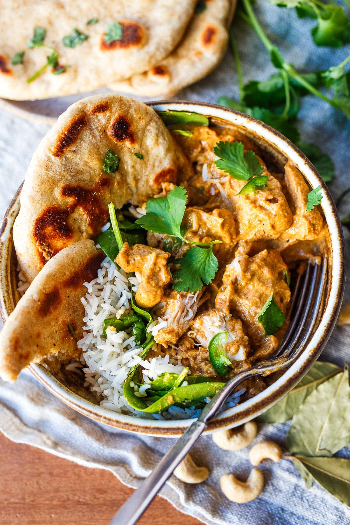 chicken korma in bowl with naan and cilantro