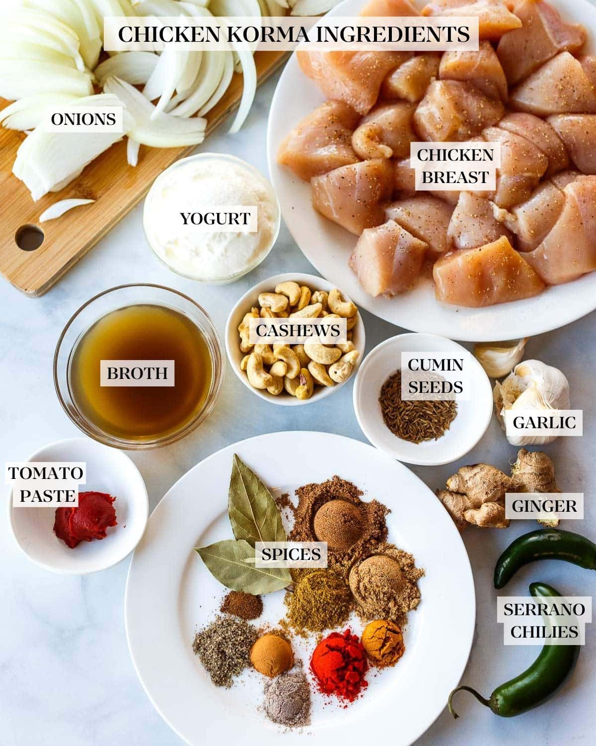 ingredients for chicken korma on counter - boneless chicken, sliced onions, cashews, spices, ginger, garlic, serranos