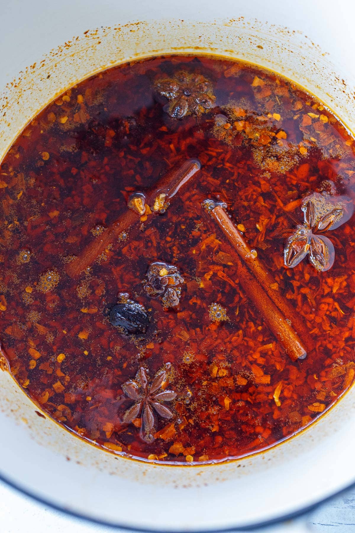 chili crisp simmering in pot with cinnamon sticks and star anise