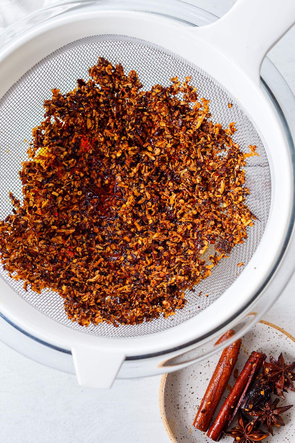 chili crisp spread out in strainer drying