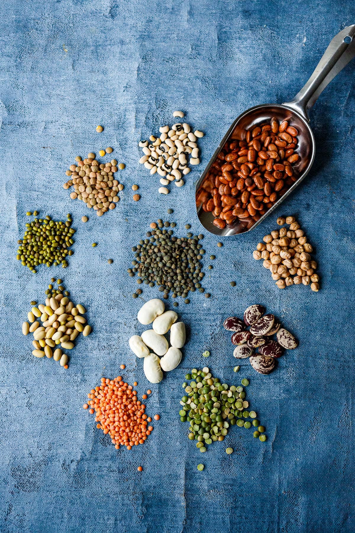 a variety of beans and legumes on a blue background.