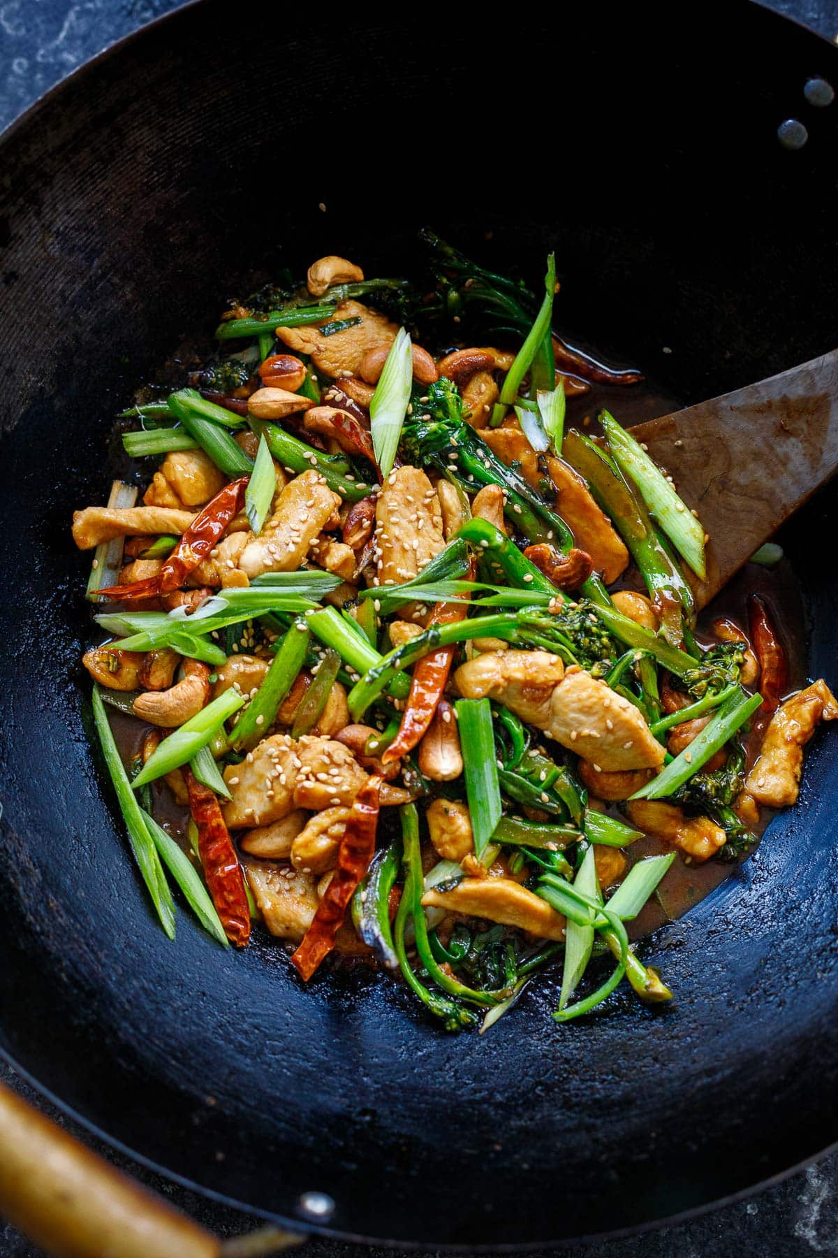 szechuan chicken stir fry in wok with vegetables, chilies, sesame seeds