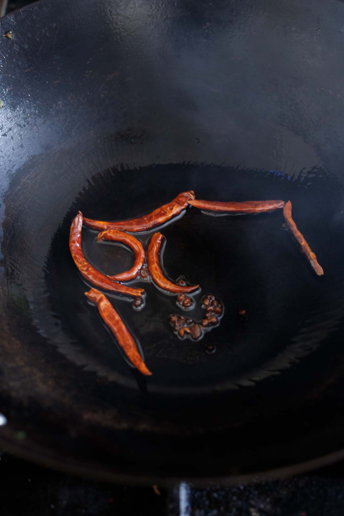 dried chilies and szechuan peppercorns frying in wok pan