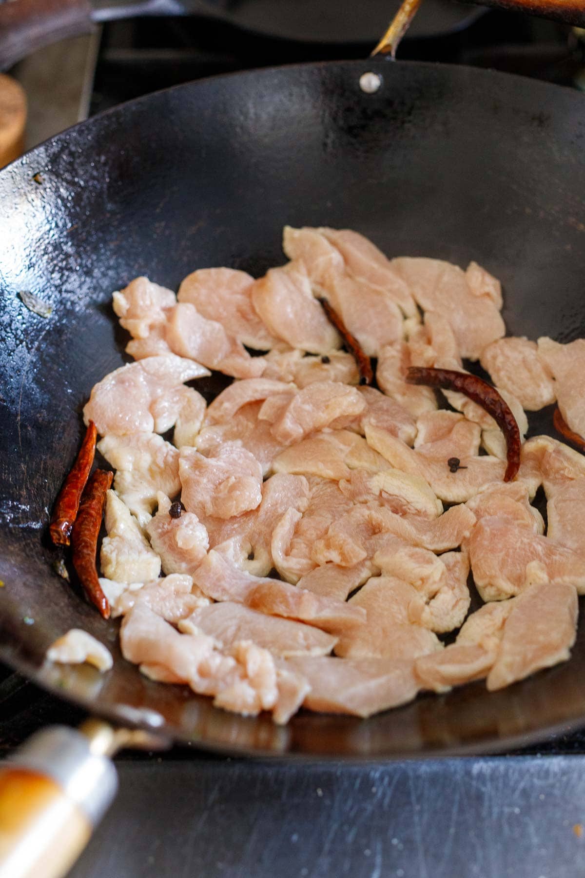 layer of chicken added to wok pan with dried chilies