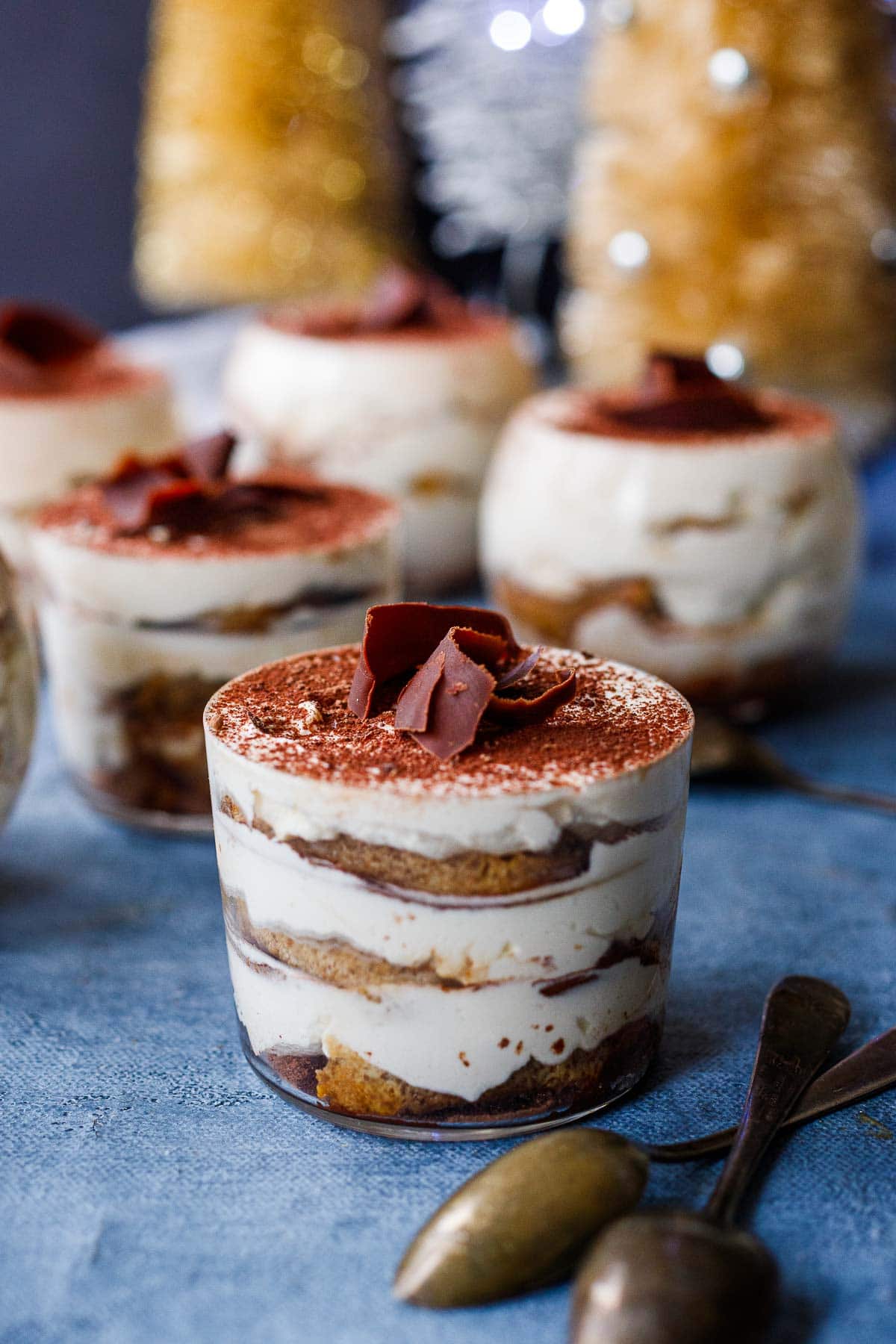 A side view of tiramisu in a glass with layers of ladyfingers, whipped mascarpone, cocoa powder and chocolate shavings.