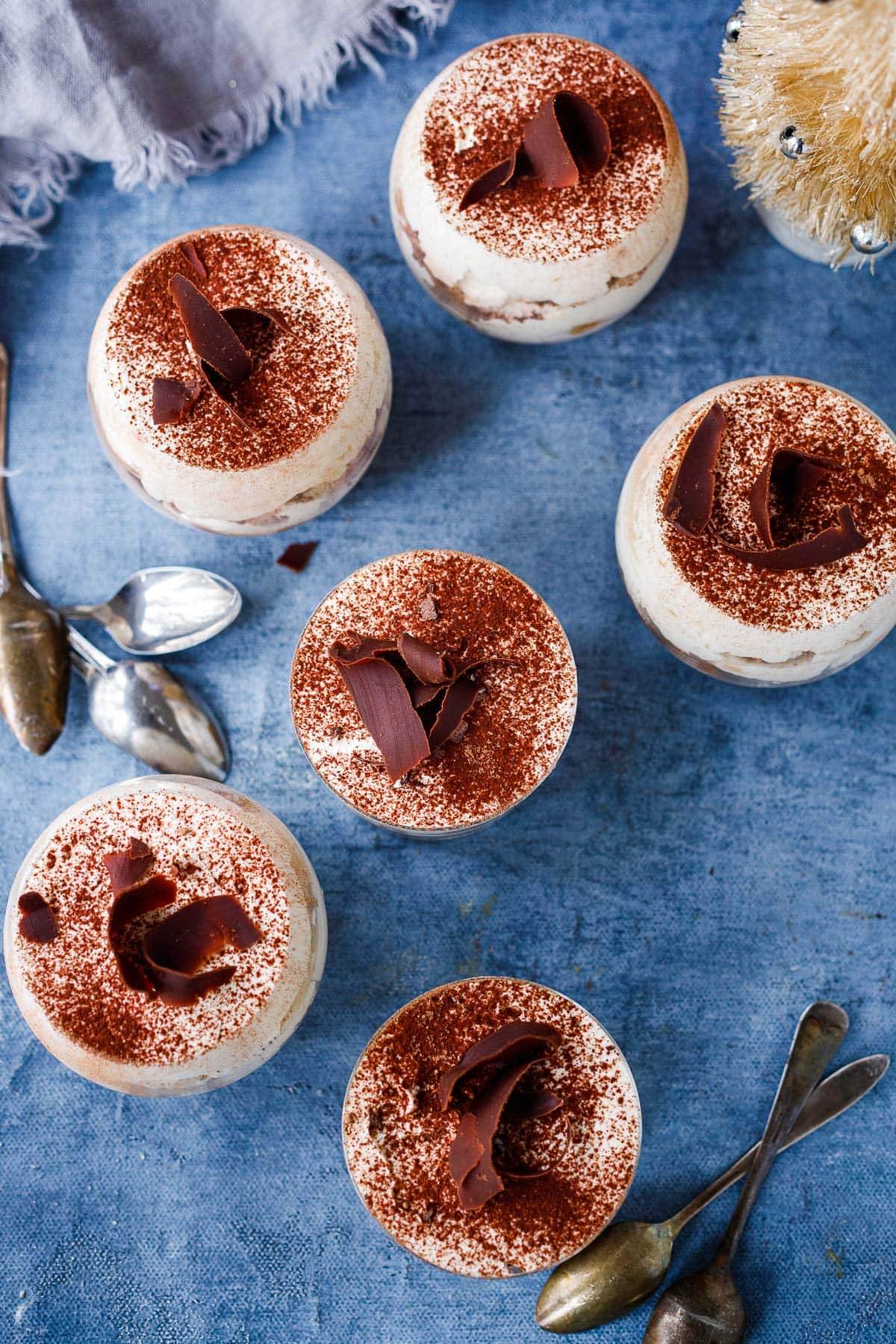 tiramisu in glasses each with cocoa powder and chocolate shaving garnish on top