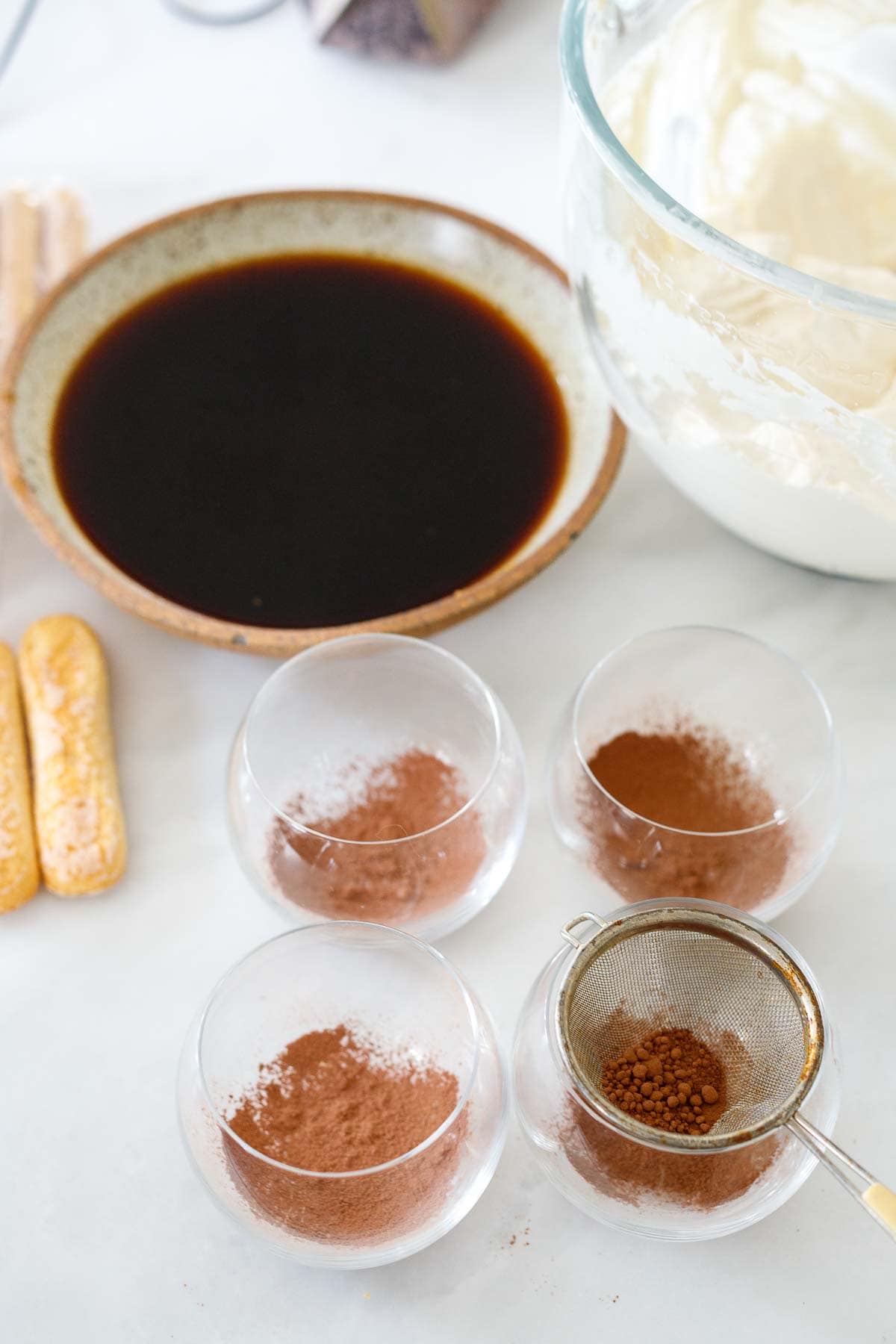 coffee mixture in bowl next to glasses with cocoa powder dusting in bottoms of glasses