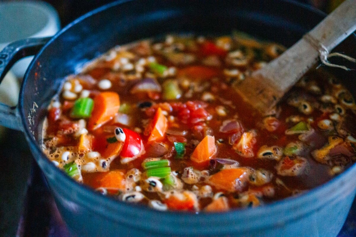 black eyed pea soup simmering in pot with wood spoon.