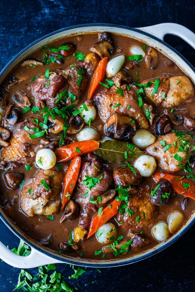 Easy & delicious, Coq Au Vin is a French chicken stew braised in a red wine sauce with cremini mushrooms, onions, carrots, and herbs.