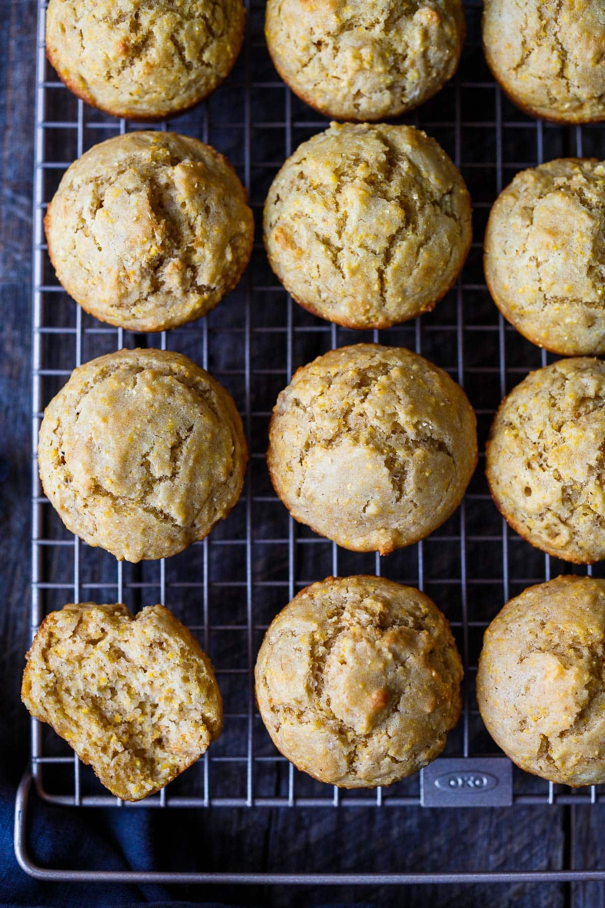vegan cornbread muffins on cooling rack with one split in half to show light and chewy texture.