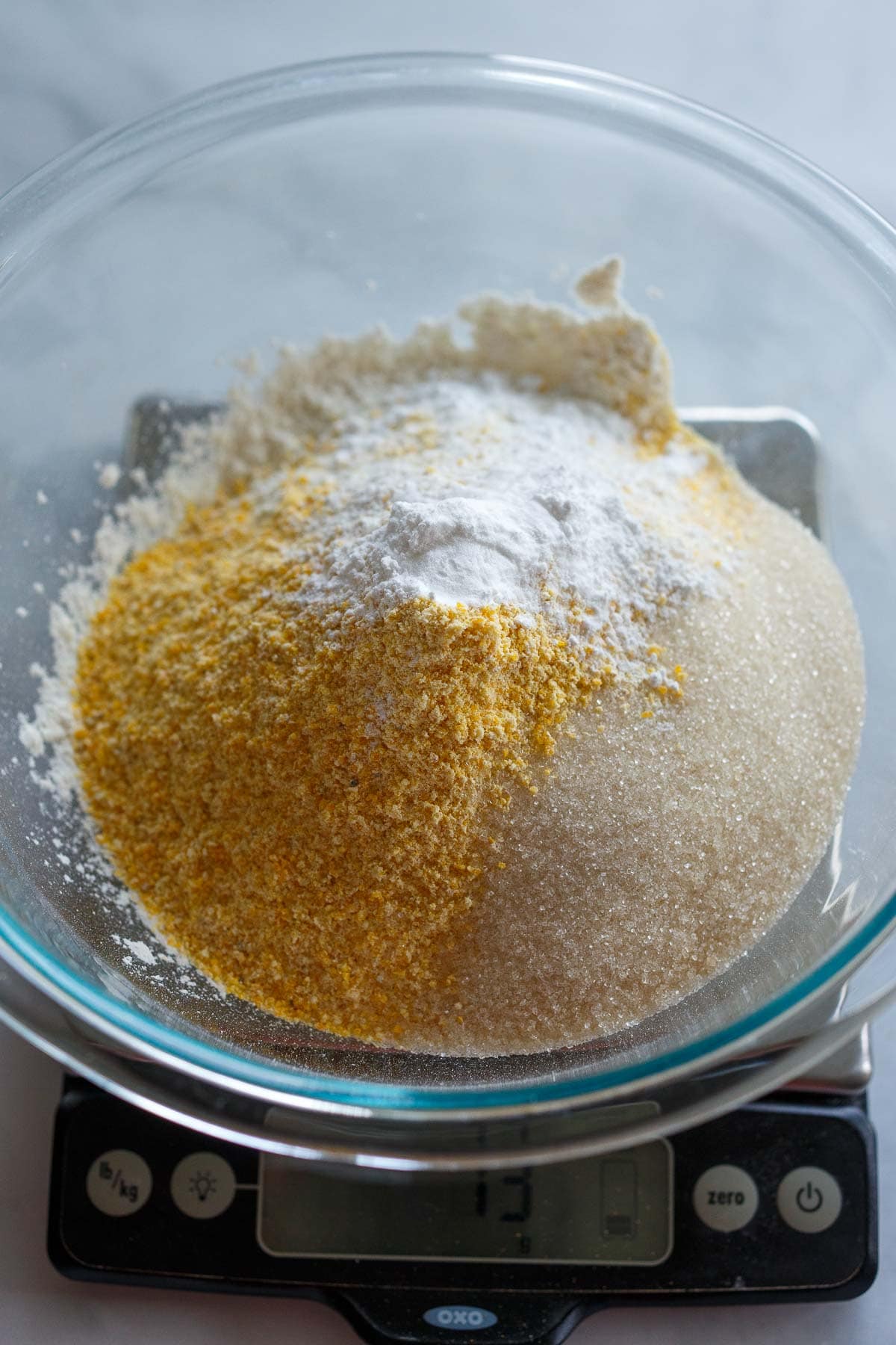 dry ingredients for vegan cornbread muffins in glass mixing bowl- cornmeal, sugar, flour.