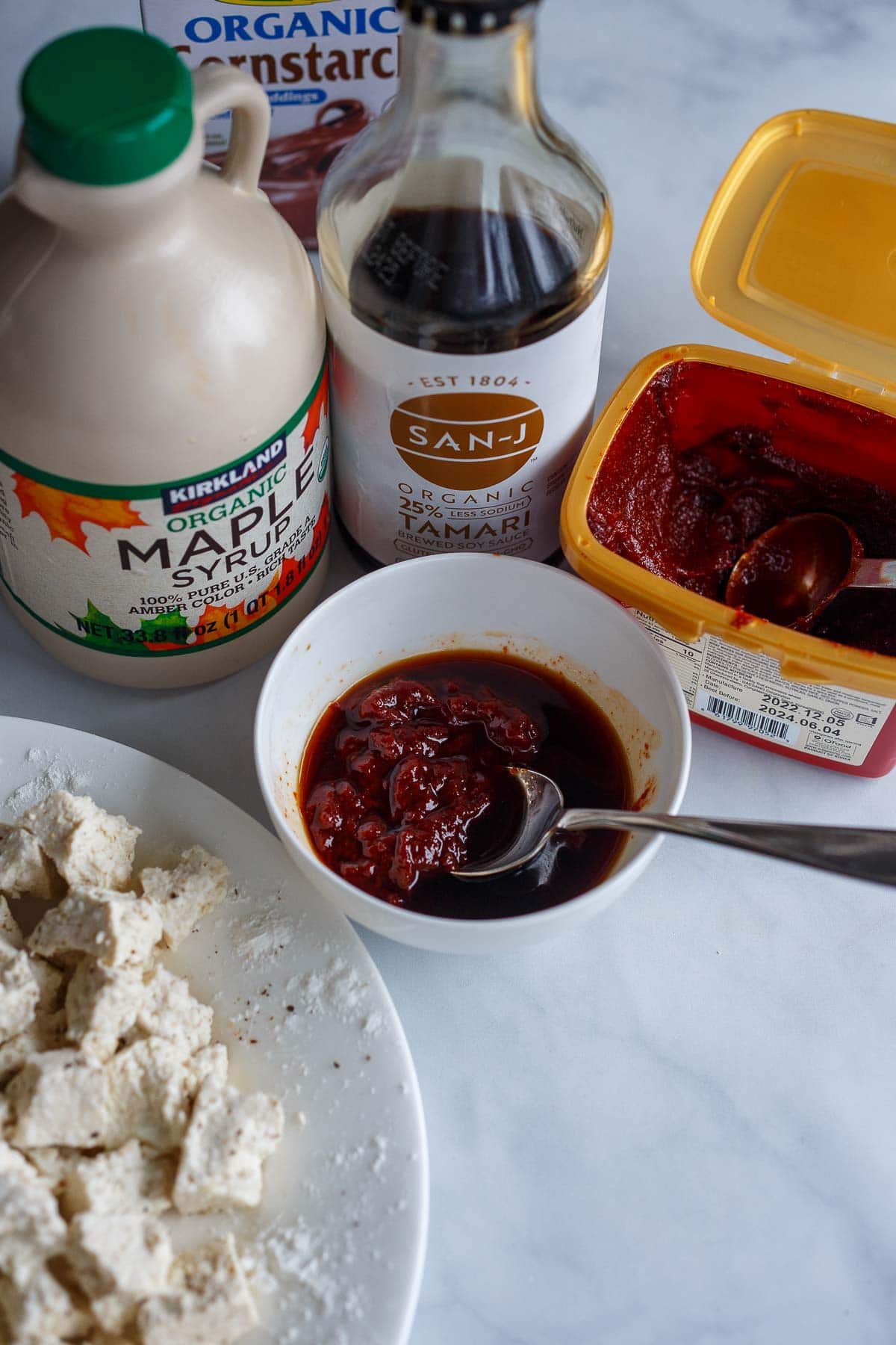 small bowl with gochujang, soy sauce and maple syrup mixed together with spoon, beside other peanut butter ramen ingredients.