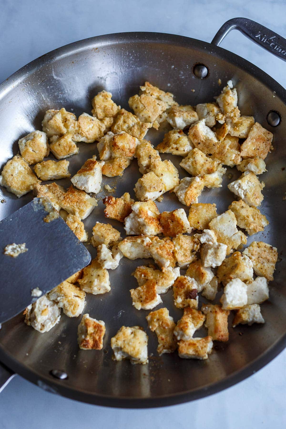 skillet with torn pieces of tofu crispy and golden, fried in pan. 