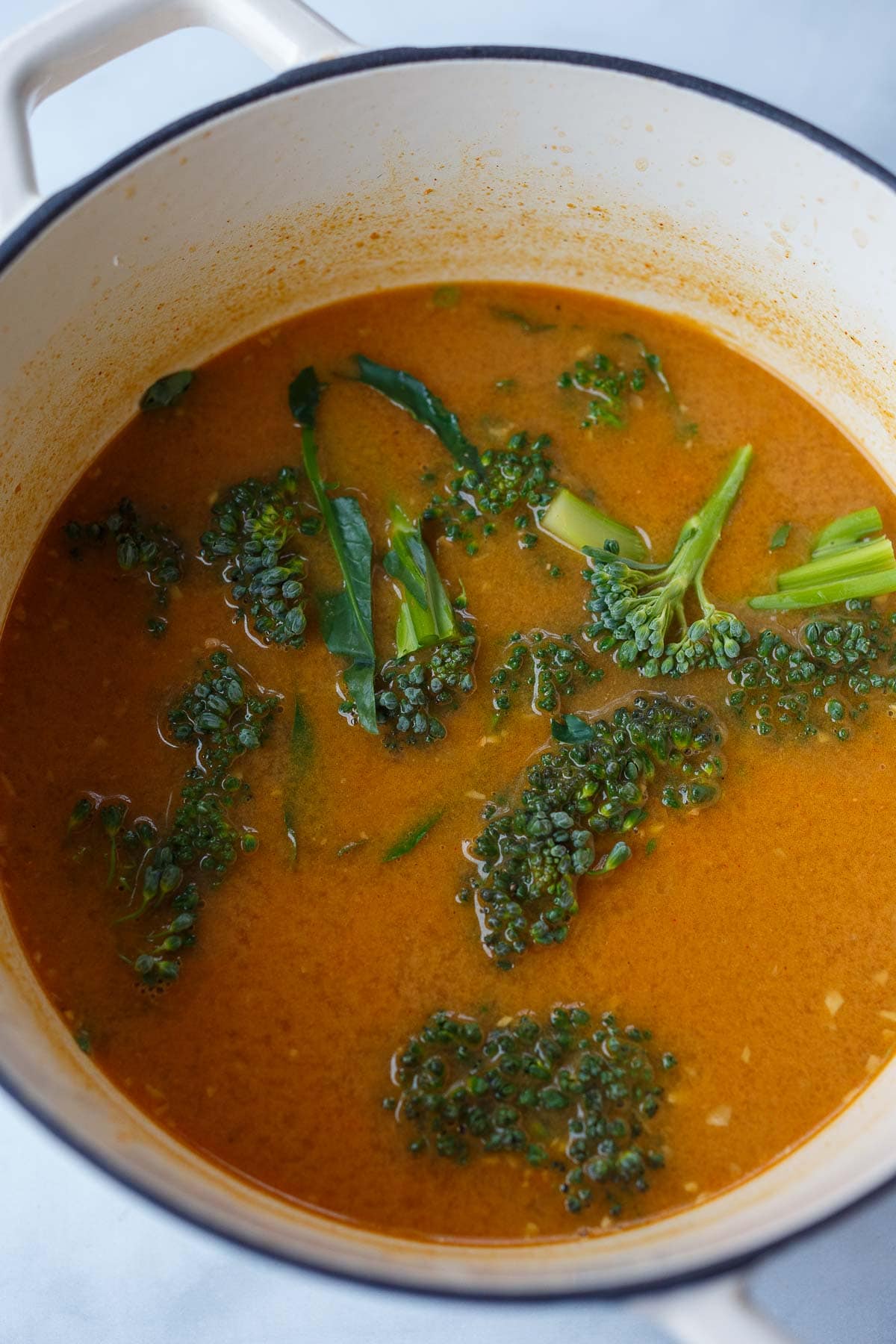 peanut butter ramen broth in pot with broccolini.