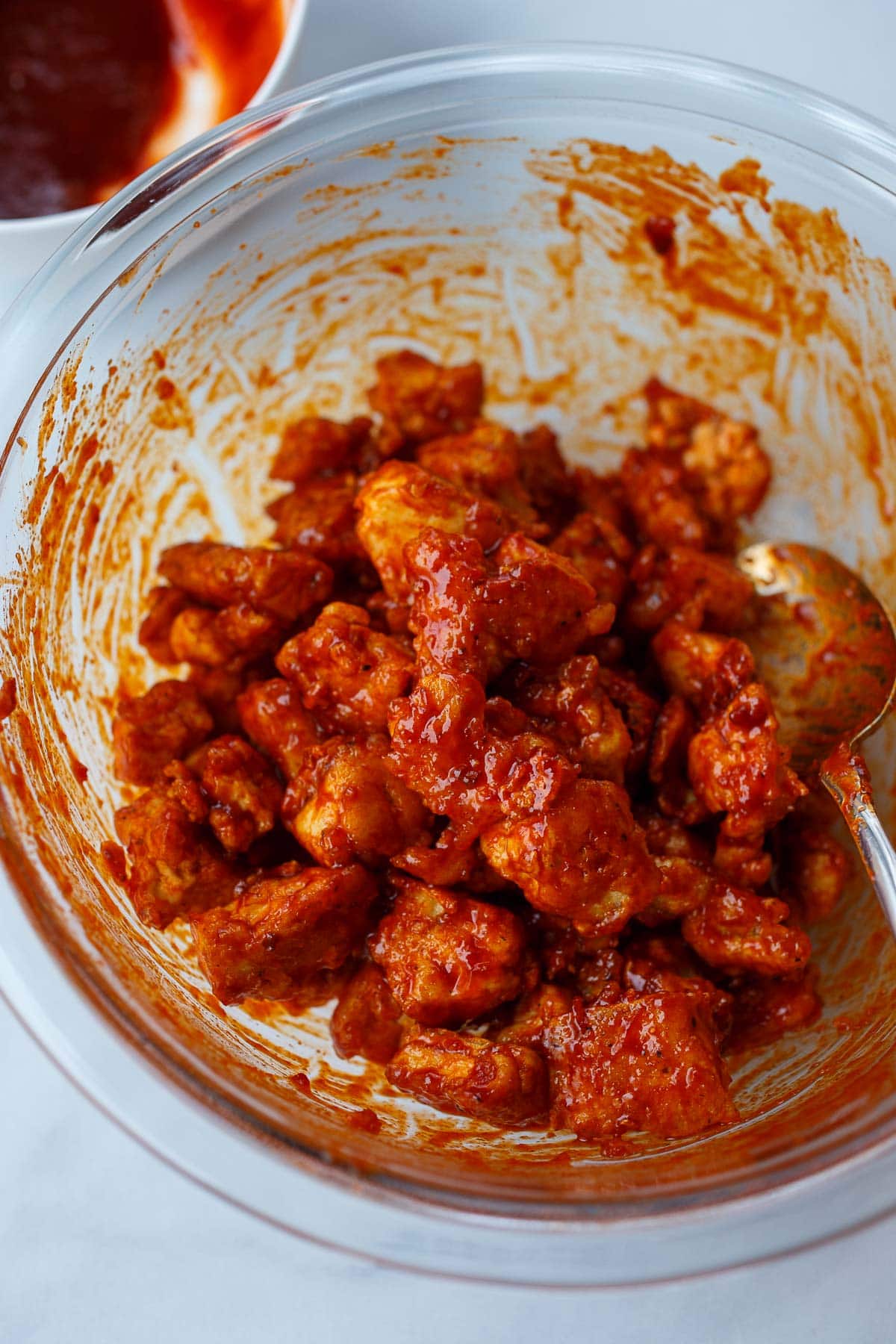 glass mixing bowl with crispy tofu covered in gochujang sauce. 