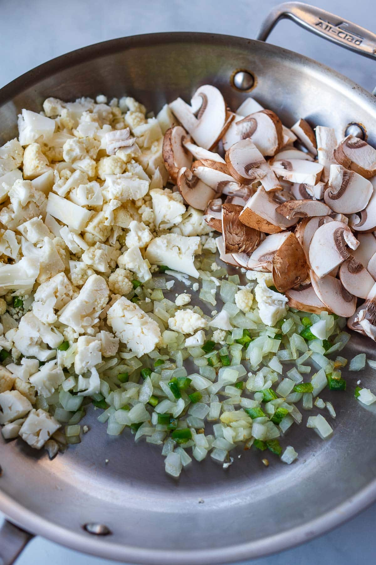 chopped mushrooms and cauliflower in skillet with diced onions and jalapeno.