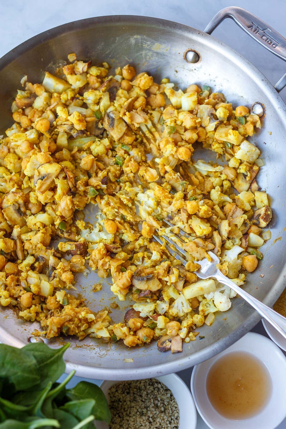 fork in pan used to mash chickpeas with spices and vegetables.