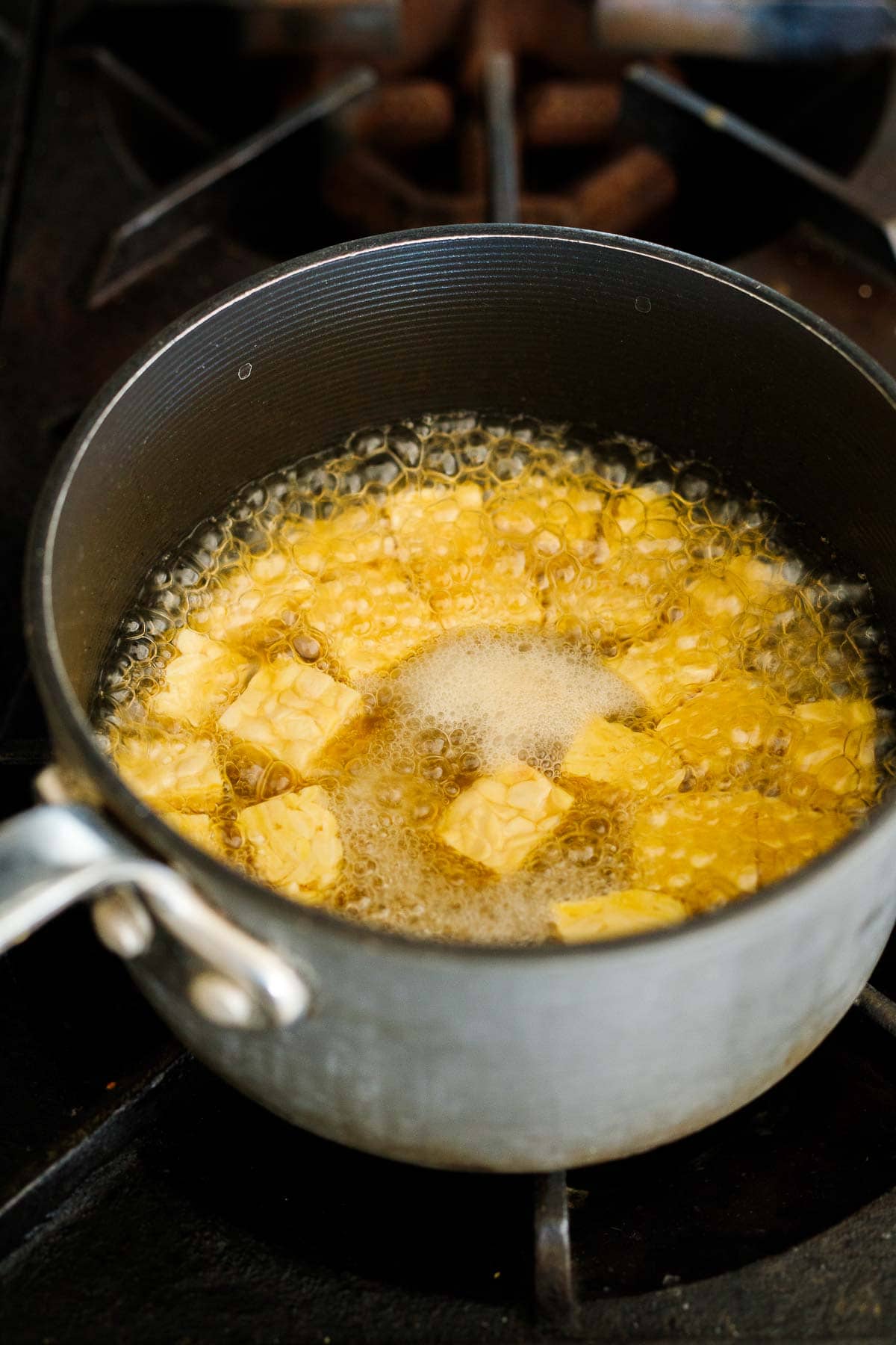 boiling tempeh with soy sauce and water in pot.