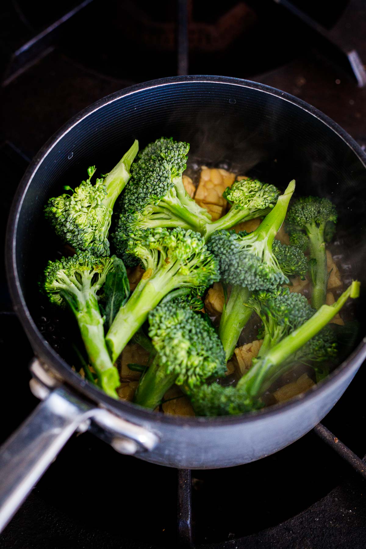 fresh broccoli added to pot of steamed tempeh.