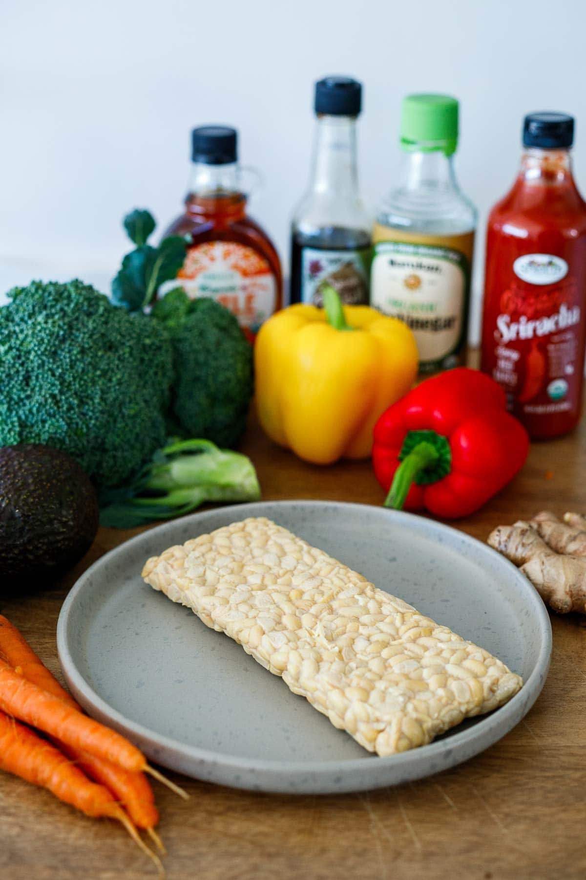 ingredients for crispy sesame tempeh- tempeh block, veggies for the bowl, sauces like sriracha, rice vinegar, soy sauce, maple syrup.