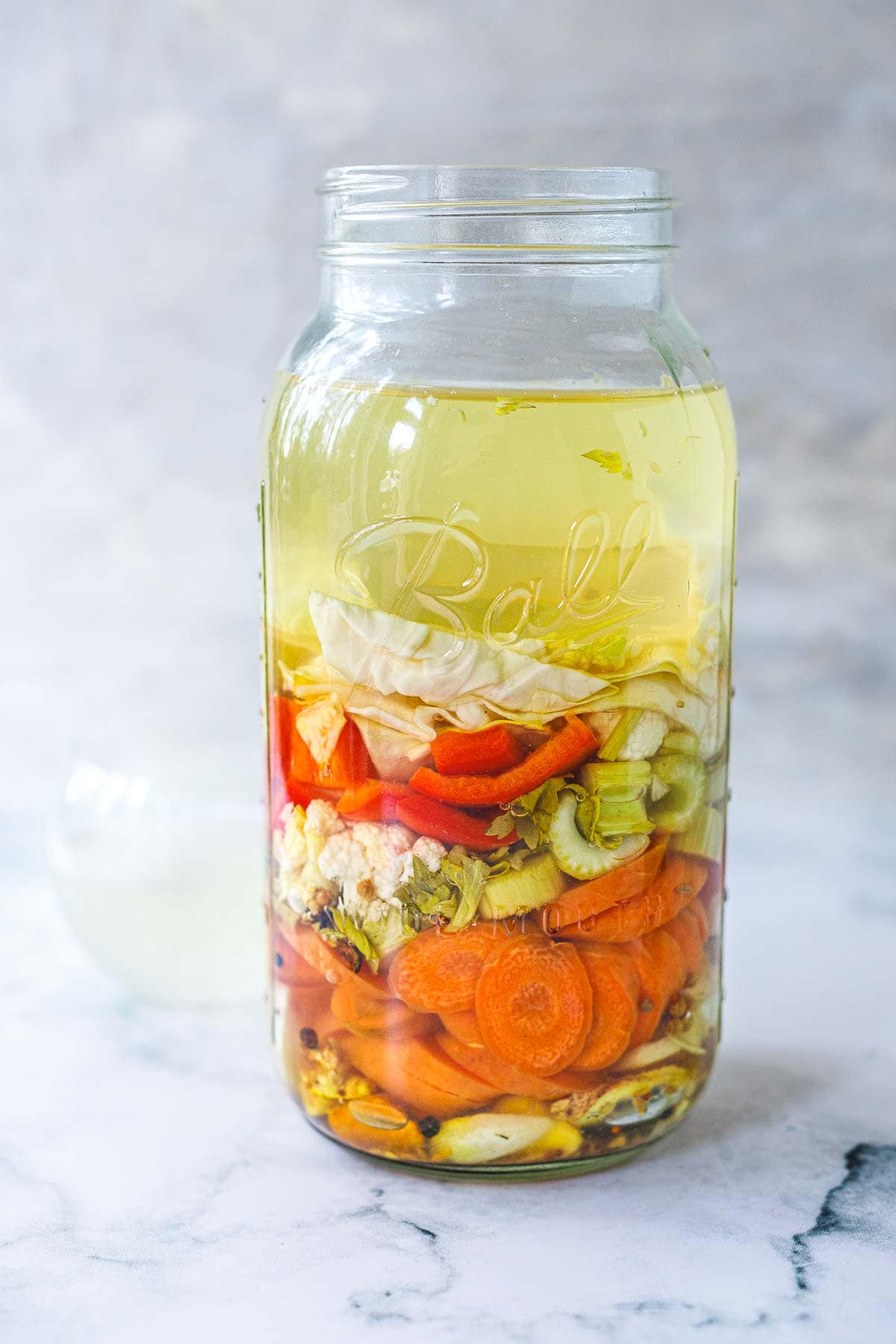jar of veggies and liquid fermented to create a gut shot - cabbage leaves, celery, carrots, red pepper, cauliflower.