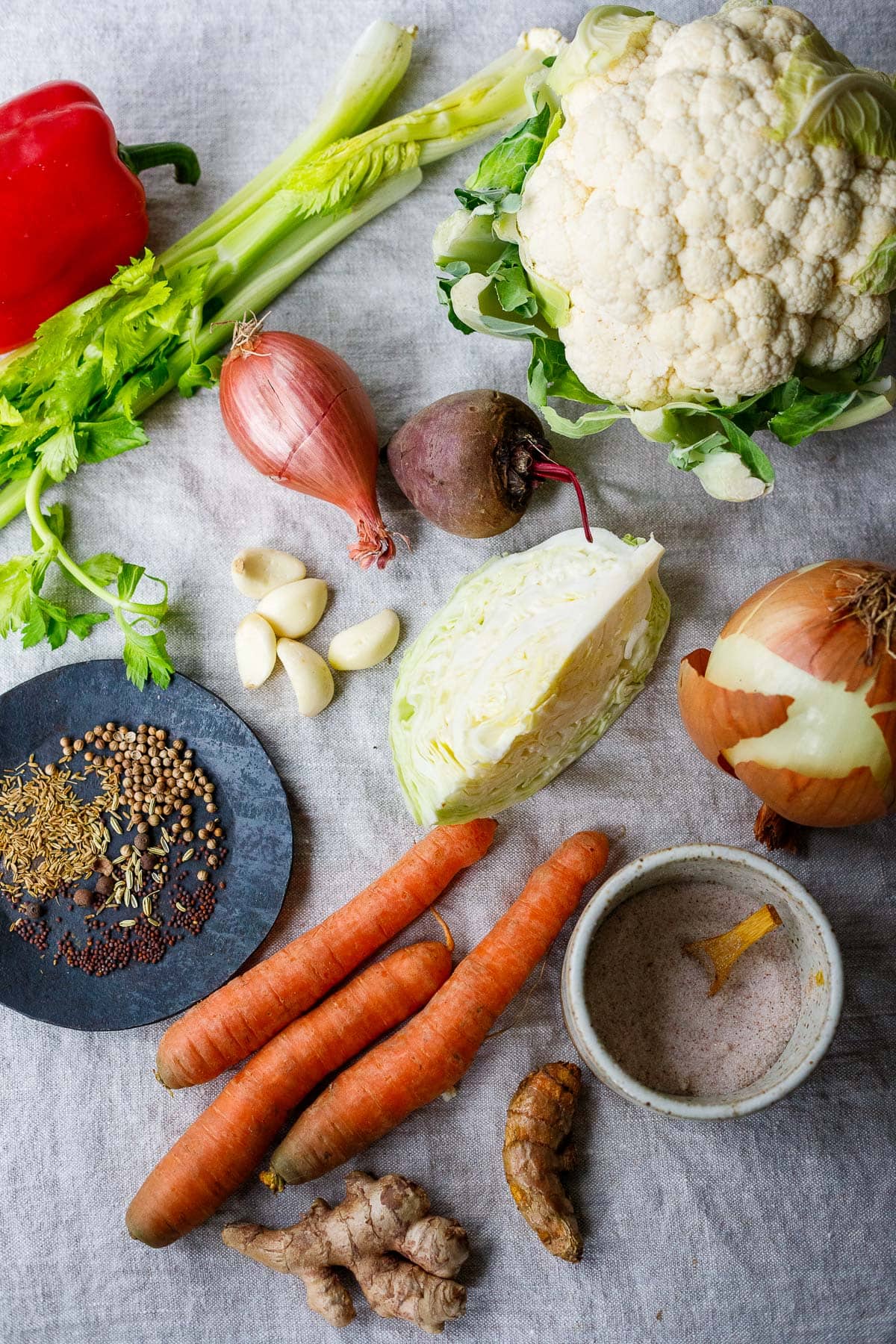 ingredients needed for making a homemade gut shot laid out on cloth - vegetables, whole spices, salt.