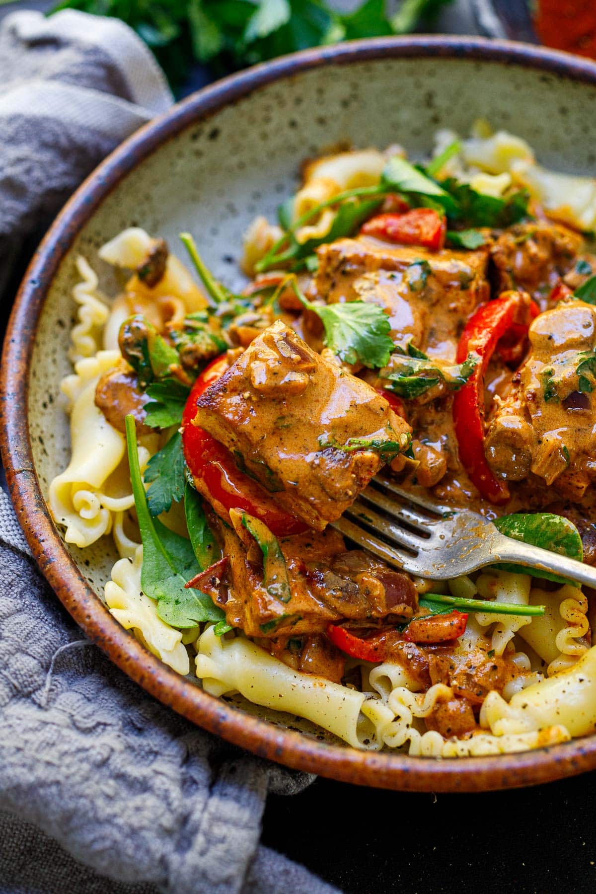 paprikash with tofu served over plate of pasta, garnished with parsley.