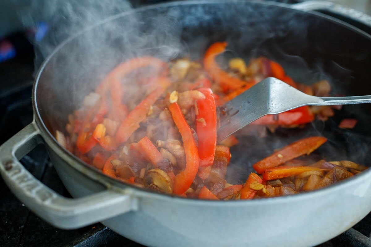 vegetables sautéing in pan - red bell peppers, onions, mushrooms. 