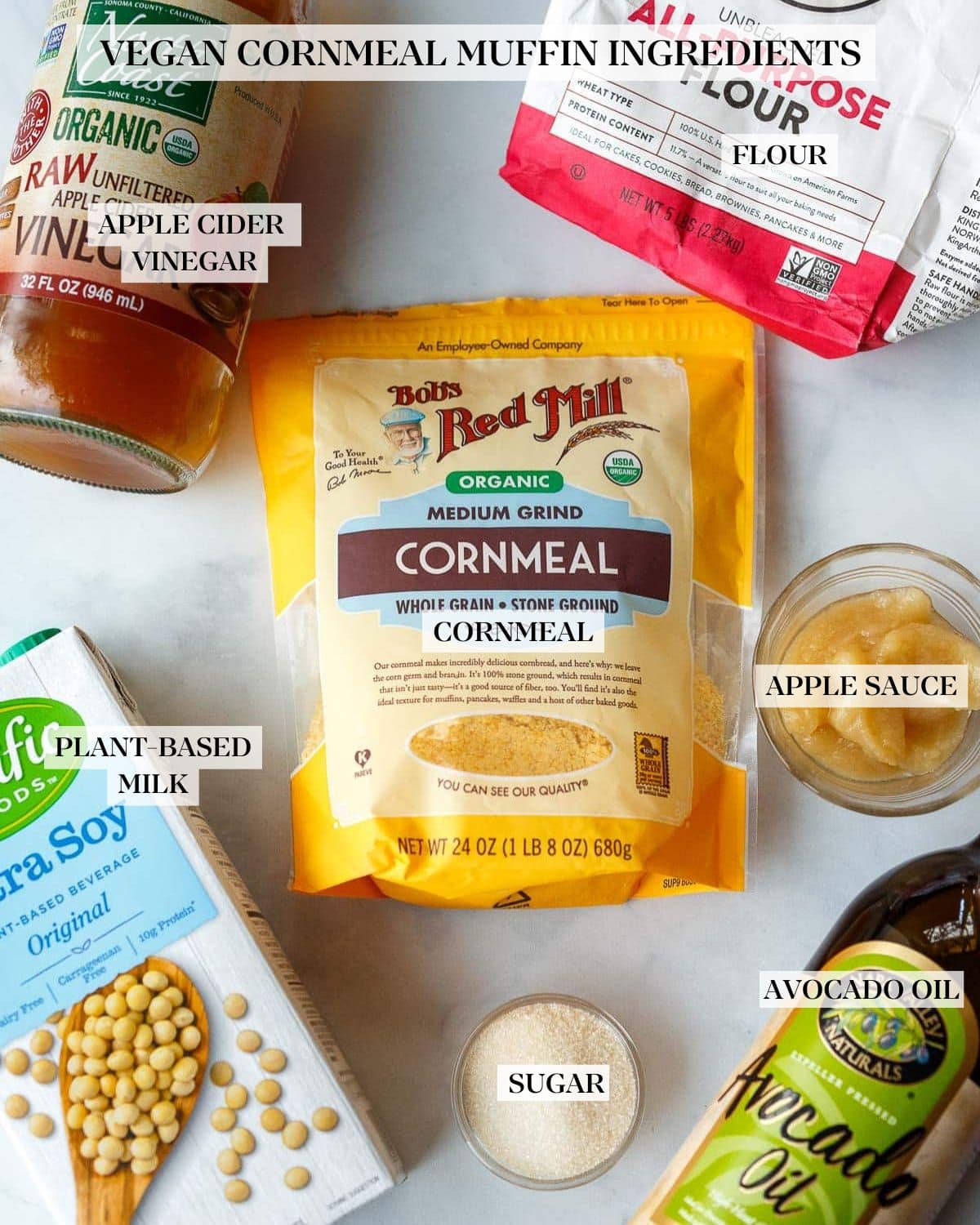 ingredients for vegan cornbread muffins laid out on table - cornmeal, flour, applesauce, vinegar, soy milk, sugar, avocado oil.