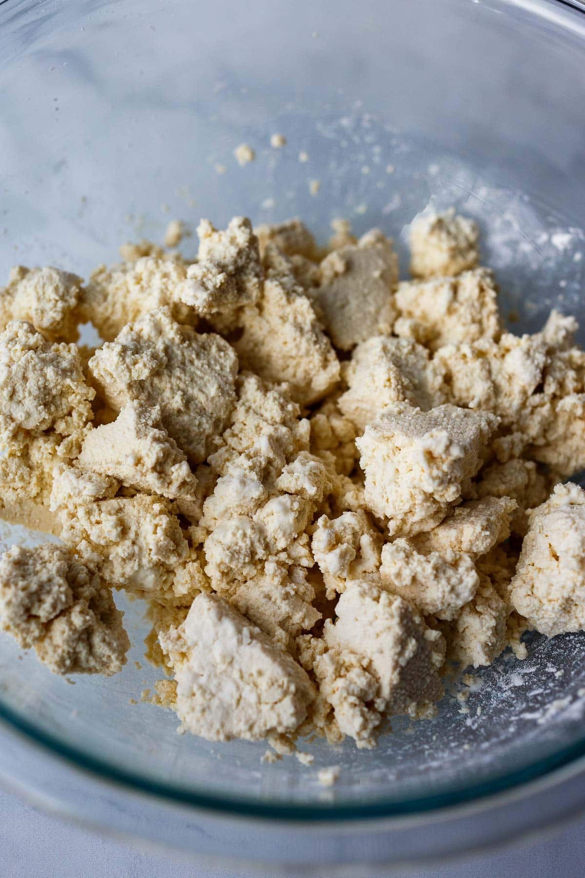 torn pieces of tofu in mixing bowl, tossed with cornstarch for frying.