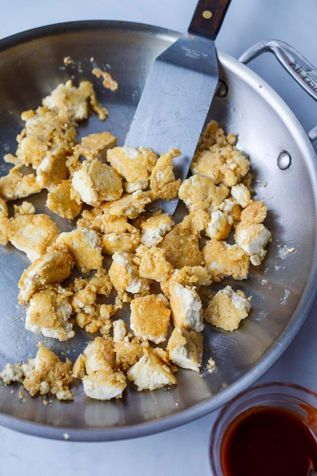 tofu pieces frying in pan with crispy edges.