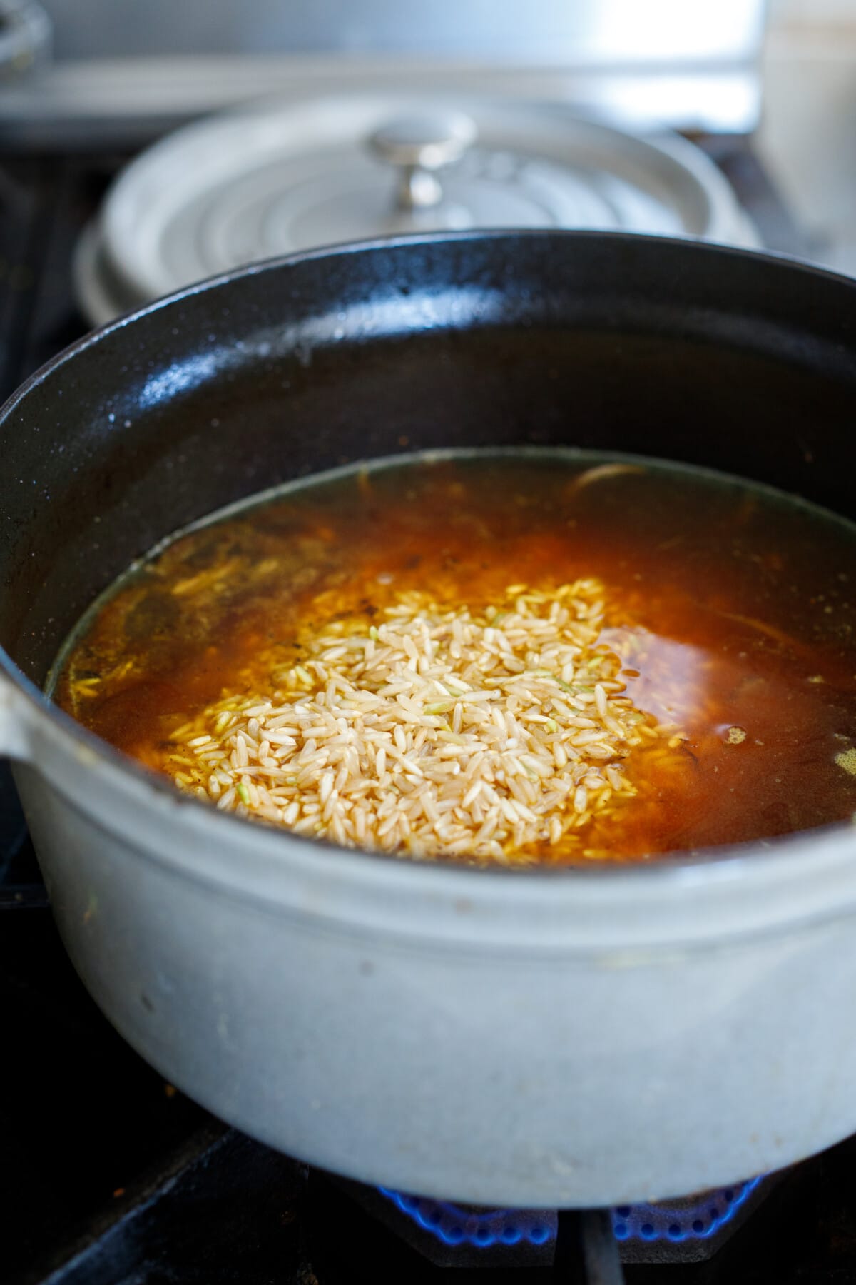 basmati rice added to dutch oven with broth to make Moroccan rice pilaf.