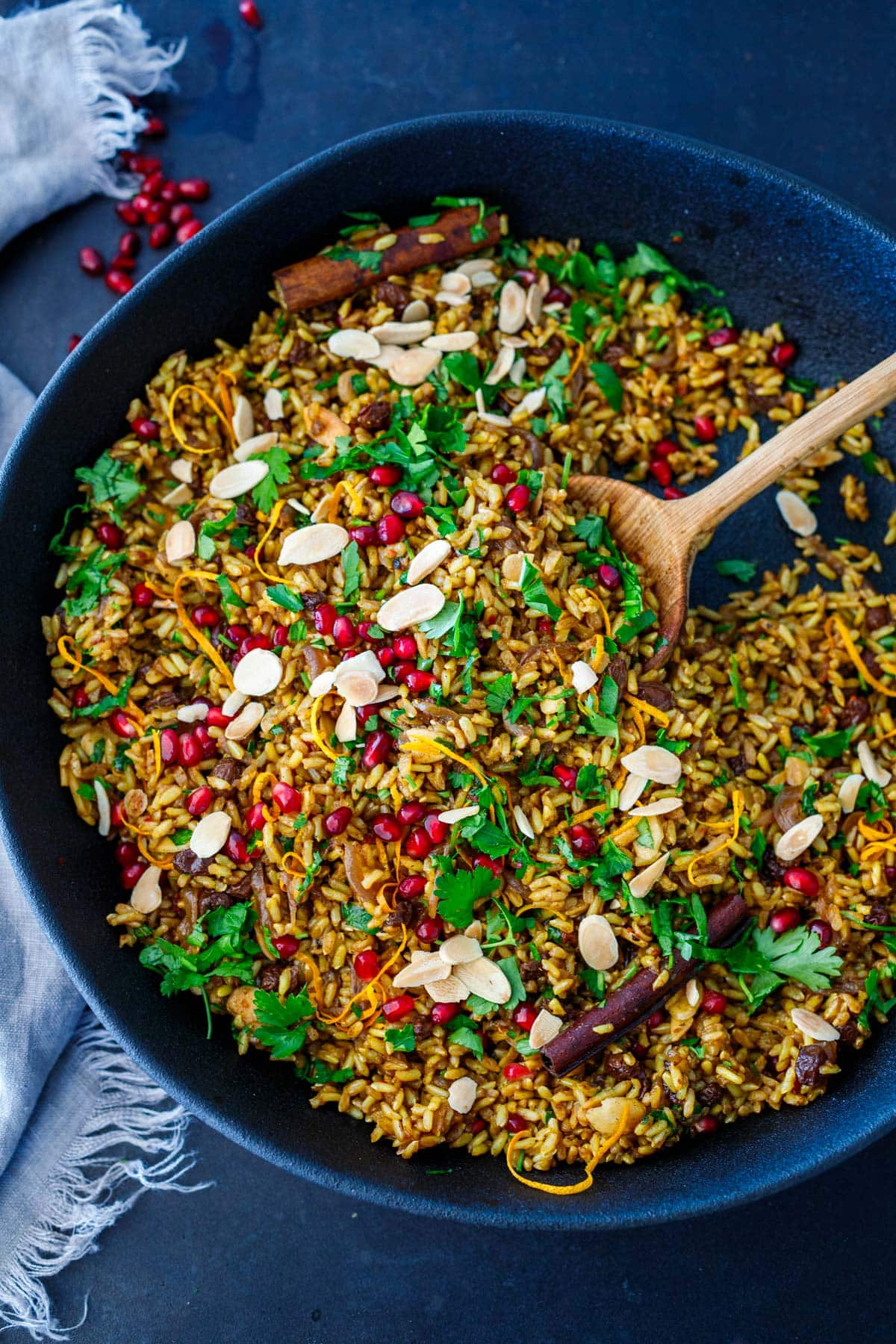Moroccan rice pilaf in large skillet garnished with parsley, pomegranate seeds and slivered almonds.