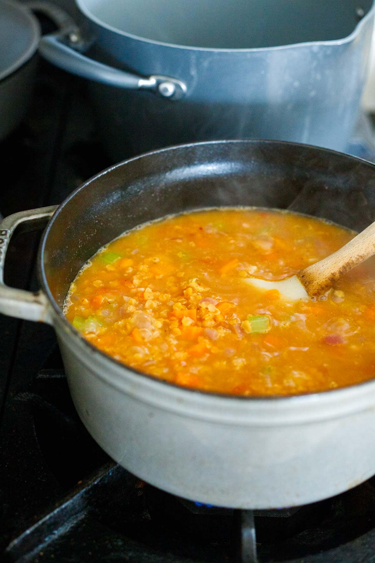 red lentil soup simmering on stove in dutch oven.