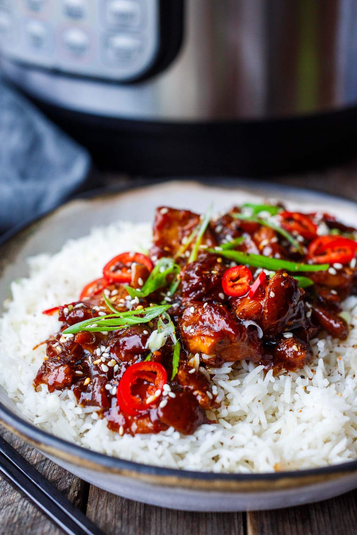 instant pot teriyaki chicken on steamed jasmine rice garnished with chilis and scallions.