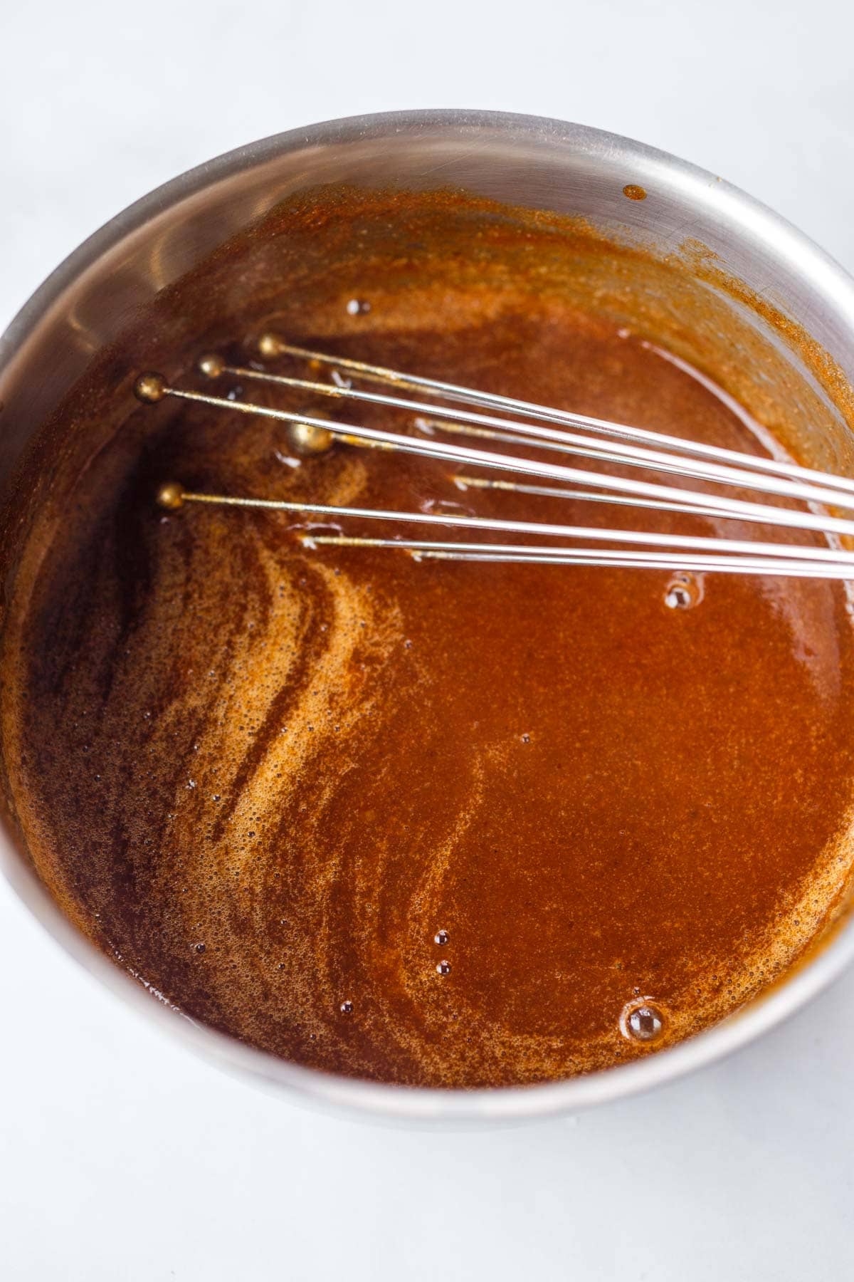 whisking homemade vegan oyster sauce in saucepan.