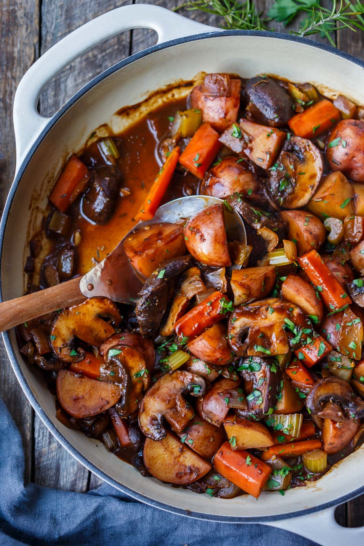 vegetable stew in pan with potatoes, carrots, mushrooms, onions, celery, garnished with minced parsley. 