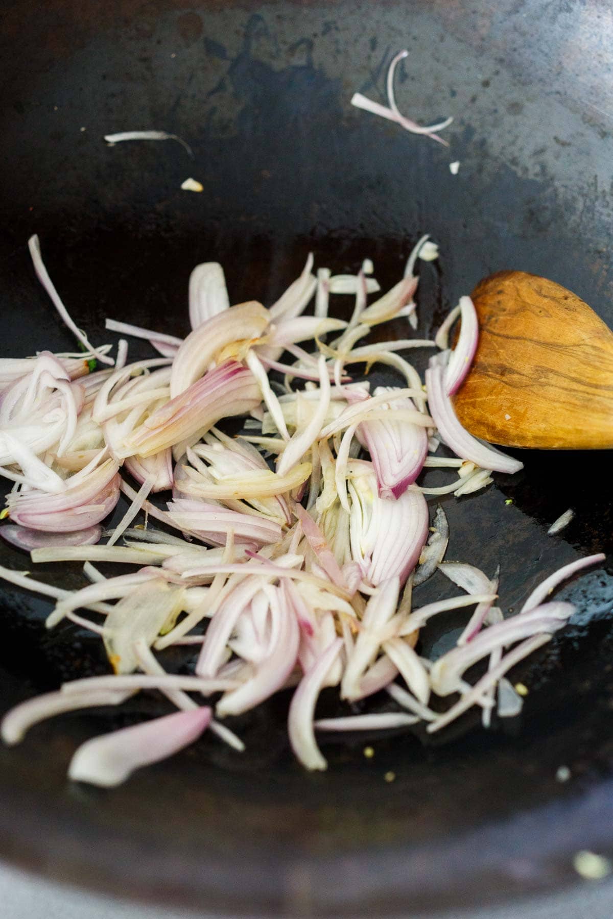 thinly sliced shallots cooking in wok.