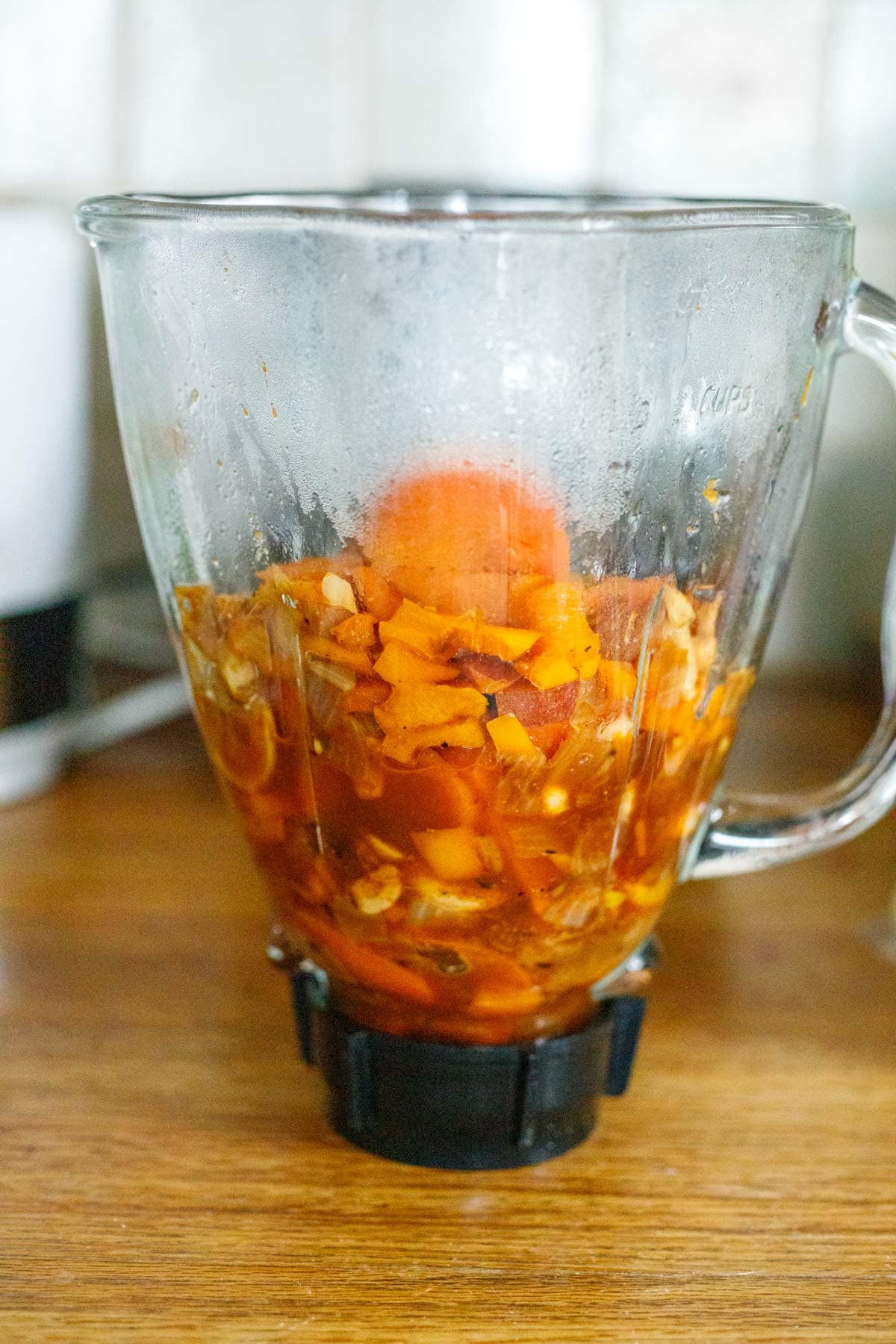blender with cooked orange veggies added to it.